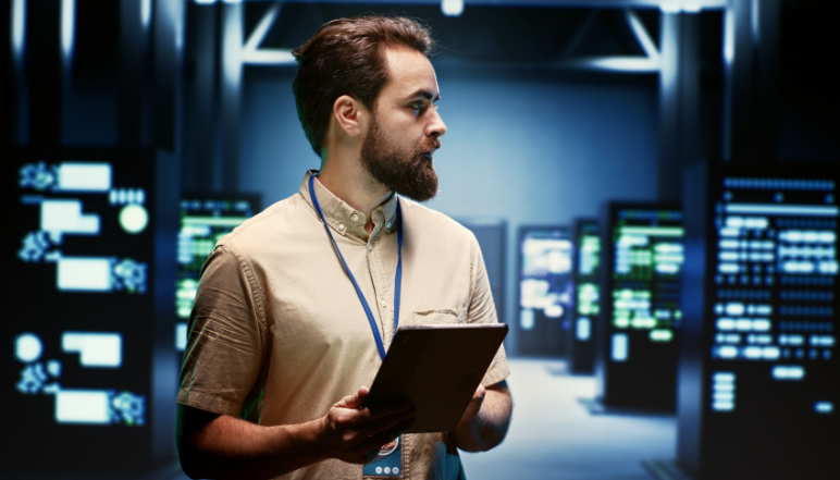 Man with tablet in server room with blinking server racks.